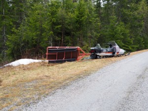 De sneeuwscooter en vervoersbakje liggen er verlaten bij
