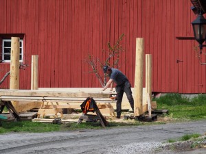 Hij bouwt een nieuwe hut naast zijn schuur. Mooie bouwstijl! Er komen karren met boomstammen voorbij