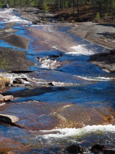 Ondanks dat er amper nog water stroomt, zie je stroomversnellingen. Het is al een aantal weken zonnig warm (voor Nederlandse zeurpieten: voor Noorse begrippen), er komt meer dan genoeg water naar beneden donderen. We zien verderop pas waar dat naar toe gaat