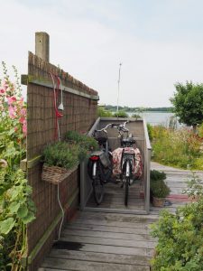 De fietsen kunnen zo in de fietskist worde gereden. Er komt nog een grijs zeil over de top, dat aan de voorkant tot op de vlonder doorloopt. Dan is vooral mijn dure elektrische fiets beschermd tegen de zilte omgeving hier