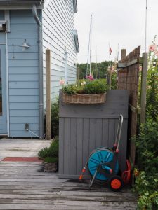 5. Dit is de hogere achterkant van de fietskist waar een bloembak aan hangt. Precies op de hoek van de schutting is nog ruimte voor ons watersysteem, waar het IJsselmeerwater doorkomt om de tuin te besproeien. De pomp staat helemaal achter op de vlonder bij het Elzenkatje aan de rand van de Zuiderhaven